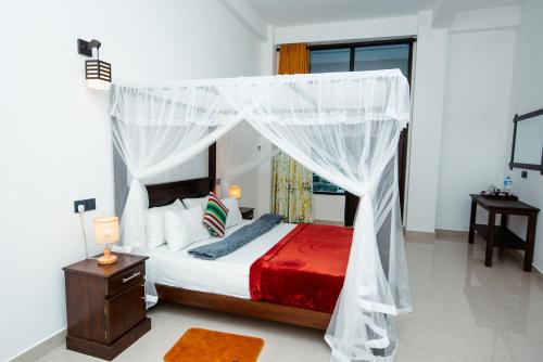 a bedroom with a bed with a canopy at Adams Peak Inn in Adams Peak