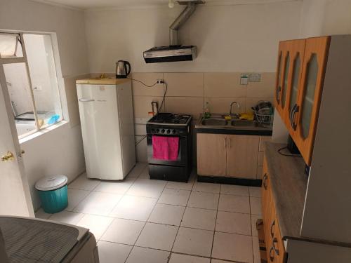 a small kitchen with a stove and a refrigerator at Hospedaje JM in Chillán