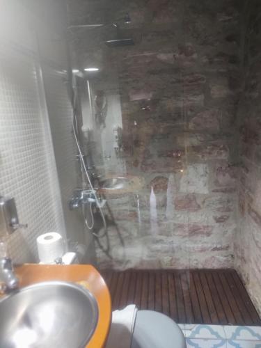 a bathroom with a sink and a stone wall at Petrino Rodo in Karpenisi