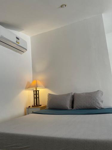 a bedroom with a bed and a lamp on a table at The Family Suite at the Mactan Airport in Pusok