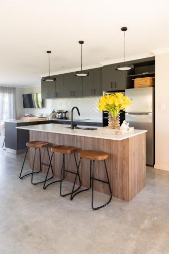 a kitchen with a counter with stools and a sink at 44onRoaring - in the Huon Valley in Surveyors Bay