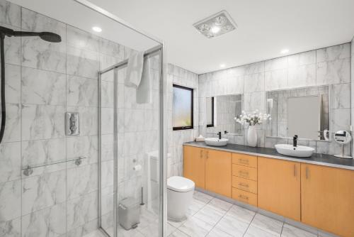 a bathroom with a shower and two sinks and a toilet at Tree Top Views - Magnificent 4 Bedroom House - 3 Minutes to MONA in Rosetta