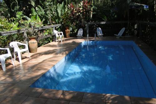 una piscina con sillas blancas y una mesa en Pousada do Oasis, en Morretes