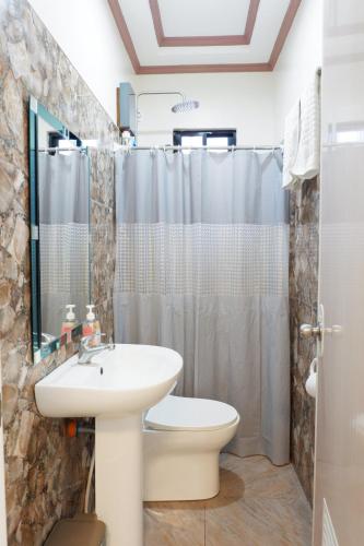 een badkamer met een wastafel, een toilet en een douche bij JUN's INN in Oslob
