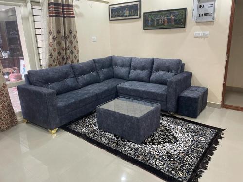 ein Wohnzimmer mit einem blauen Sofa und einem Teppich in der Unterkunft Narayan associates aries in Bangalore