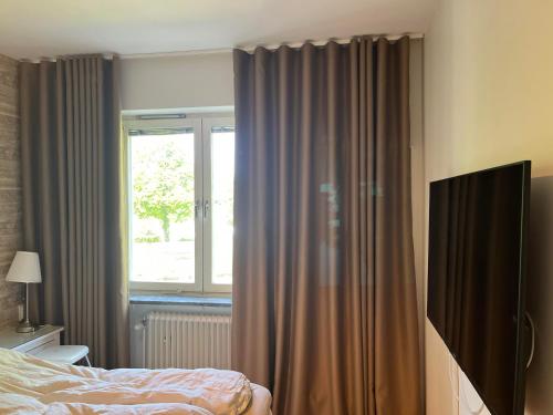een slaapkamer met een bed en een raam met gordijnen bij Mysig lägenhet eurovision 2024 in Malmö