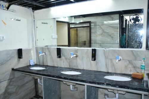 a public bathroom with three sinks and a mirror at KSHIPRA GUEST HOUSE in Ujjain