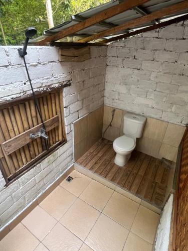 a bathroom with a toilet in a brick wall at Tetebatu Jungle Vibes in Tetebatu