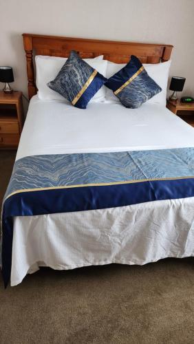 a large bed with blue and white pillows on it at Bed & Breakfast @ Unsworth Heights Albany in Auckland