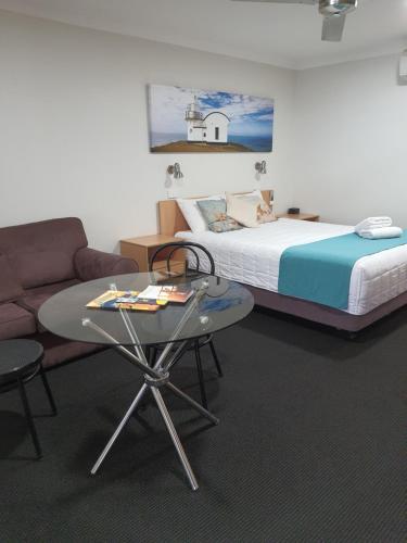 a bedroom with a bed and a table and a couch at Aston Hill Motor Lodge in Port Macquarie