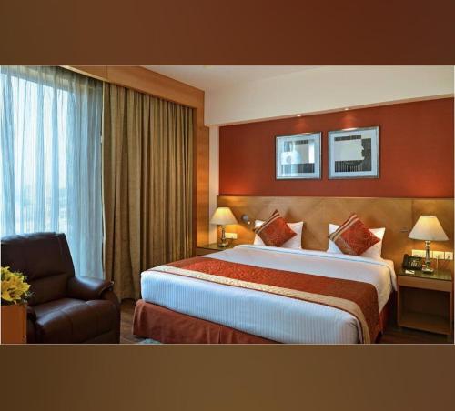 ein Hotelzimmer mit einem großen Bett und einem Stuhl in der Unterkunft HOTEL FLAMINGO in Jaipur