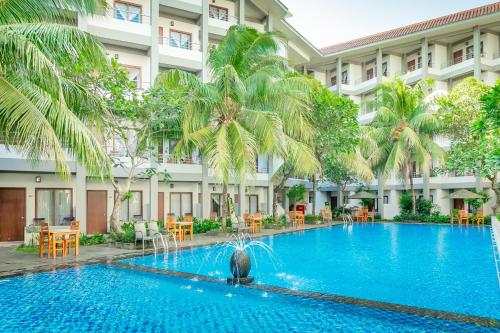 a swimming pool in front of a building with palm trees at Lombok Garden Hotel in Mataram