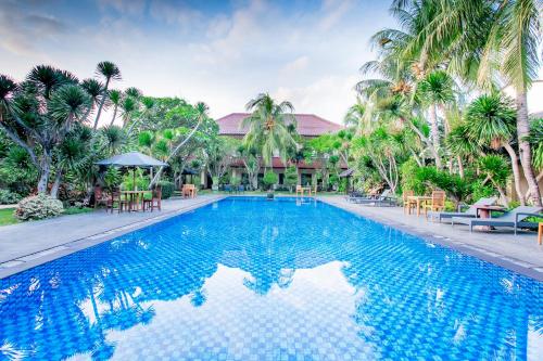 a swimming pool in front of a resort with palm trees at Lombok Garden Hotel in Mataram