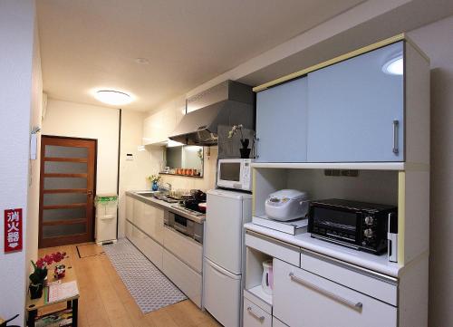 a small kitchen with white cabinets and appliances at 薫樹xiang po po inn in Kyoto