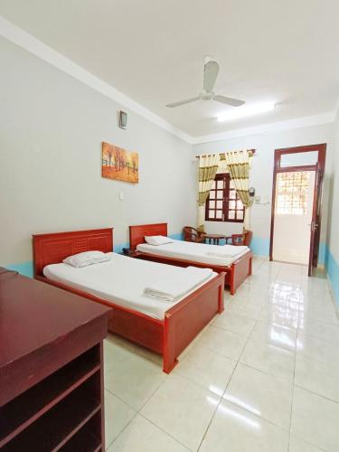 1 dormitorio con 2 camas, mesa y ventana en Nhà Khách 379, en Cà Mau