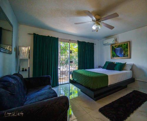 une chambre avec un lit, un canapé et un ventilateur dans l'établissement Fiwi-Own Chelsea Manor, Kingston, à Kingston