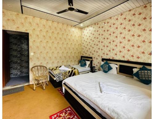 Natraj Heli Resort, Sersi في Phata: غرفة نوم بسريرين وكرسي فيها