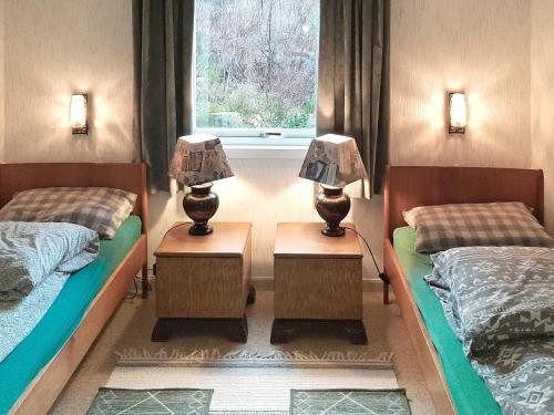 two beds in a room with two lamps on tables at Holiday home Åram in Sandvik
