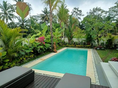 een zwembad in een tuin met bomen bij Adi Laxmi Villa Ubud in Ubud