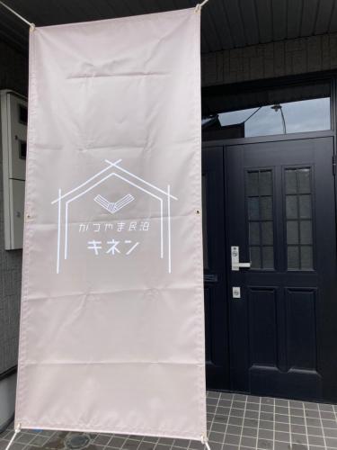 a large white sign in front of a door at かつやま民泊きねん in Katsuyama