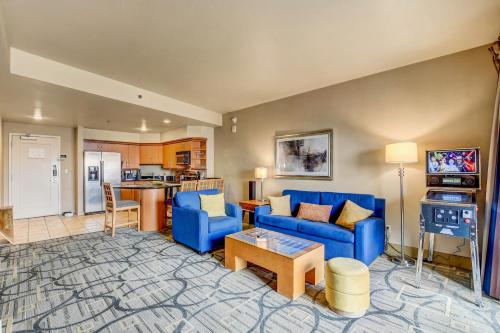 a living room with blue couches and a kitchen at Diligence at The Platinum - NO Resort Fees and Free Parking in Las Vegas