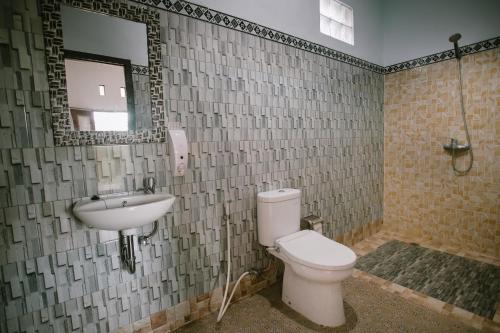 a bathroom with a toilet and a sink and a mirror at De Casa Ananda Nusa Penida in Nusa Penida