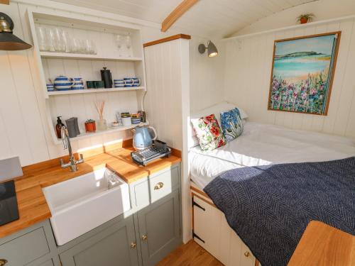 a small kitchen with a bed and a sink in a room at Lower Trewern Shepherds Hut in Penzance