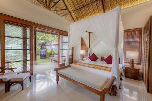 Villa Dorado - Steps from Jimbaran Beach في جيمباران: غرفة نوم بسرير مع مظلة