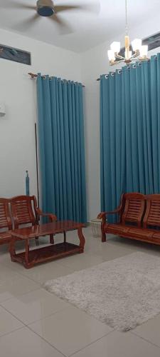 2 Stühle in einem Zimmer mit blauen Vorhängen in der Unterkunft Anggun Boutique Homestay in Kampong Jalan Bahru