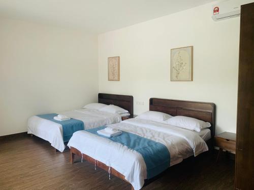 two beds in a room with white walls and wood floors at 【森林城市高尔夫别墅】高性价比，双层别墅民宿 in Gelang Patah