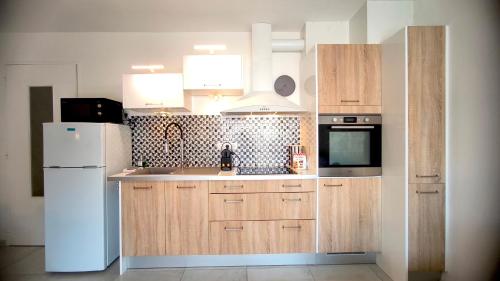 - une cuisine avec des placards en bois et un réfrigérateur blanc dans l'établissement SUNSET GARDEN - Roof Top 45 m2 Vue Mer / Cap Canaille, à Cassis