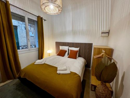 1 dormitorio con 1 cama con almohadas de color naranja y ventana en LE PETIT PECHEUR DE CASSIS, en Cassis