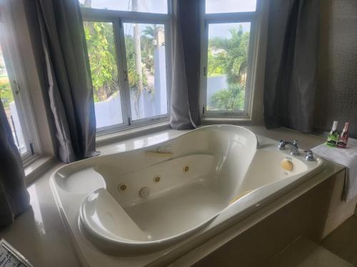 a large white tub in a bathroom with windows at Beautiful Battersea Lodge in Mandeville