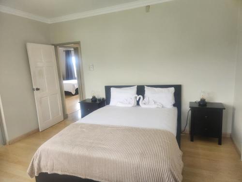 a bedroom with a large bed with white sheets and pillows at Beautiful Battersea Lodge in Mandeville