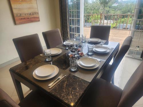 a dining room table with chairs and a table with plates and glasses at Beautiful Battersea Lodge in Mandeville