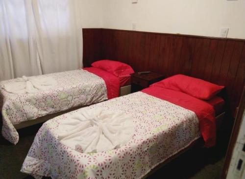two beds with red and white sheets in a room at Hotel Posada Sol in Villa Carlos Paz