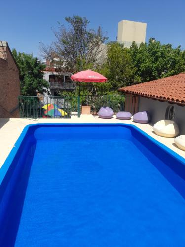 a blue swimming pool with chairs and an umbrella at Hotel Posada Sol in Villa Carlos Paz