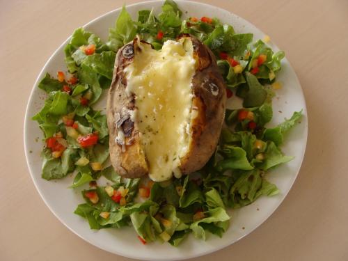a plate of food with a salad with meat and cheese at Pensiunea Taverna Bucium in Iaşi