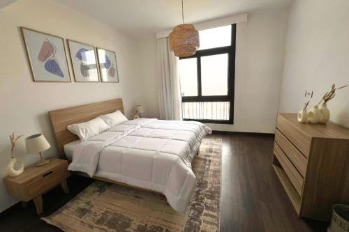 a bedroom with a large bed and a window at BambooStays Cozy 2BR at Cairo Festival in Cairo