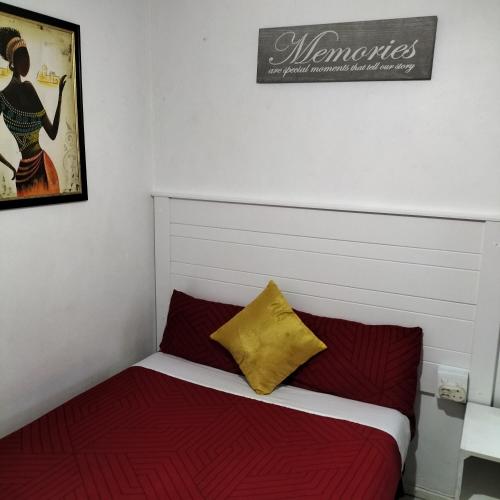 1 dormitorio con 1 cama con almohadas rojas y amarillas en Naledi homestay, en Ciudad del Cabo