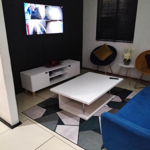 a living room with a white table and a tv at Naledi homestay in Cape Town