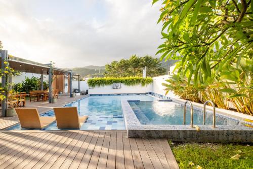 a swimming pool with two chairs and a table at Tirta Spring Villa with Hotspring Pool in Los Baños