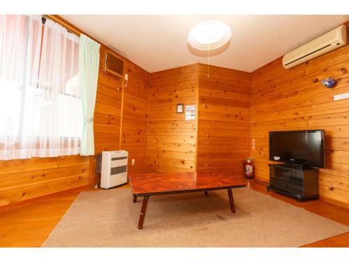 uma sala de estar com uma mesa e uma televisão em Lake Kawaguchi Rental Villa Tozawa Center - Vacation STAY 46680v em Oishi
