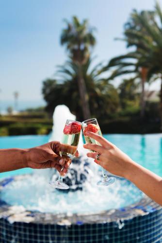 two people holding champagne glasses in front of a pool at President Hotel in Cape Town