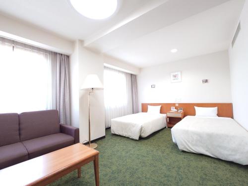 a hotel room with two beds and a couch at SAIDAIJI GRAND HOTEL - Vacation STAY 92843 in Okayama