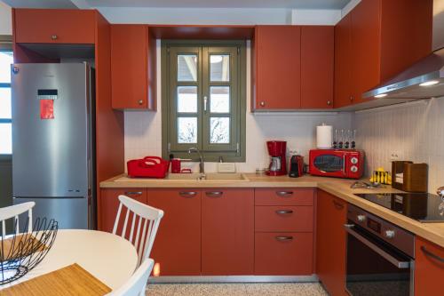 a kitchen with red cabinets and a table and a refrigerator at Villa Rosa - Luxury Villas with Panoramic Views in Lagoúdi Zía
