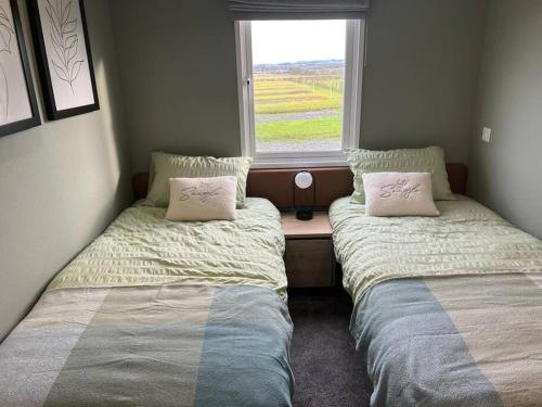 2 camas en una habitación con ventana en Eden Lodge StAndrews, peace and tranquility. en Strathkinness