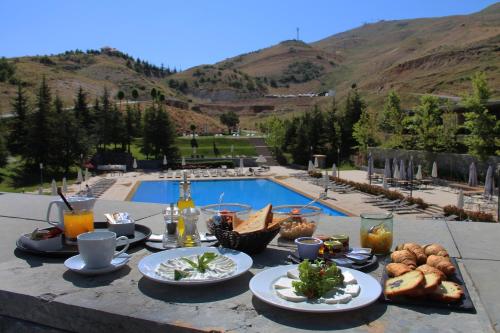a table with food and drinks next to a pool at Le Grand Chalet Zaarour in Zaarour