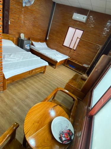 HOMESTAY HƯƠNG RỪNG في Tân Phú: غرفة بسريرين وطاولة خشبية