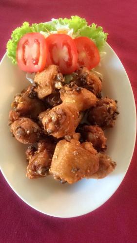 a white plate of food with tomatoes and lettuce at จอมเมือง Motel in Nan